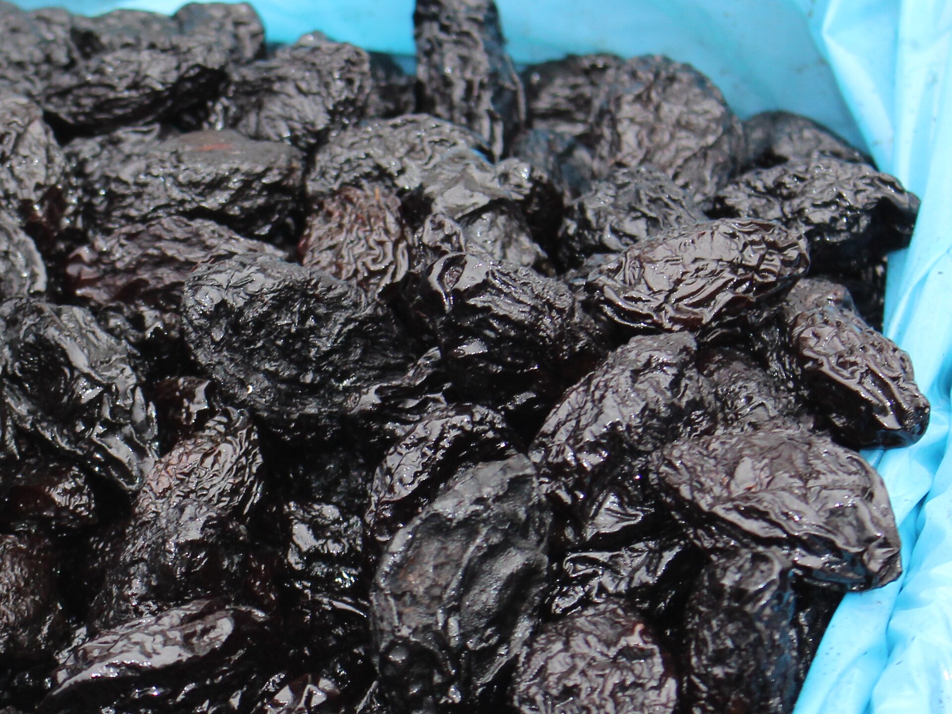 Pruneaux secs disposés dans un bol, aliment riche en fibres souvent cité pour le transit