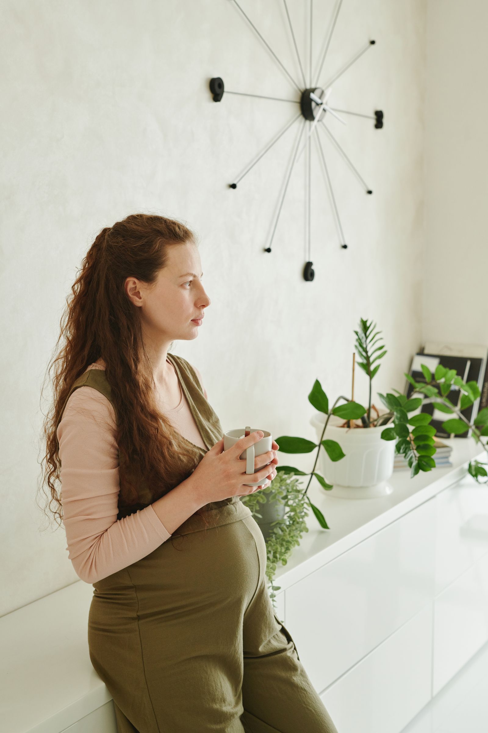 Femme enceinte sereine avec une tasse près d'une fenêtre