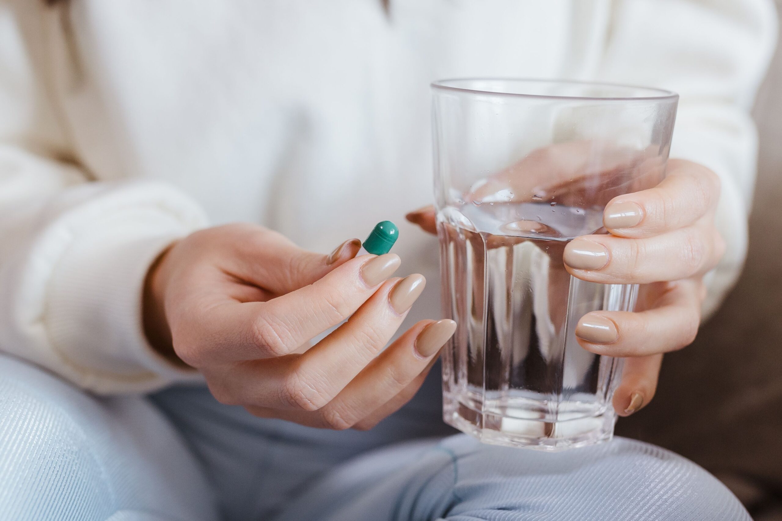 Personne tenant un comprimé et un verre d'eau