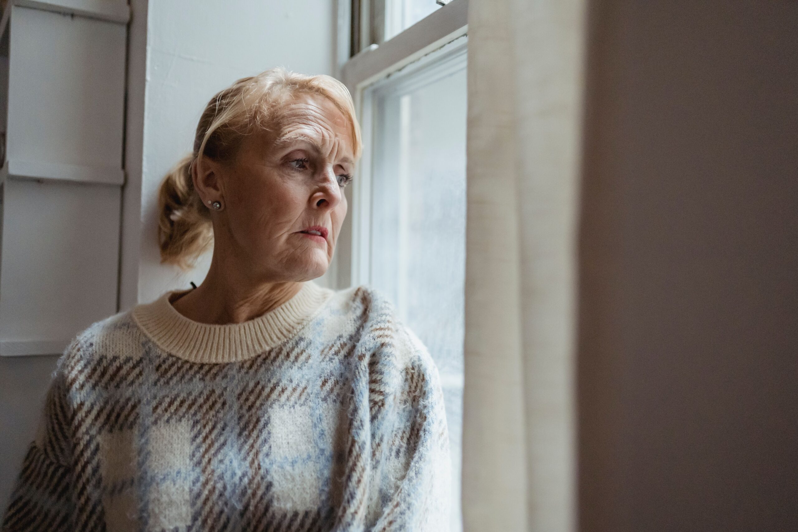 Femme d'âge mûr pensive regardant par la fenêtre